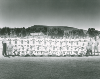 Thumbnail for 'The 1957 varsity football team poses for a photograph south of Mountaineer Gymnasium (now Paul Wright Gymnasium)'
