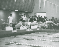 Thumbnail for 'A small crowd of spectators crowd into the Mountaineer Gymnasium pool area to watch a swim meet, ca. 1968.'