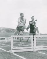 Thumbnail for 'Hurdler Jerry Ballard has a leg up on his School of Mines competitor in Mountaineer Bowl competition.  Photograph is dated 1958.'