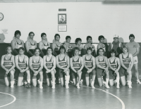 Thumbnail for 'A mid-1980s WSC wrestling team and their coaches Tracy Borah and Jack Garrison pose for a team photograph under the memorial...'