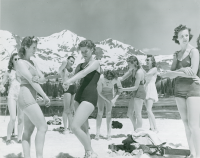 Thumbnail for 'A group of Western students in bathing suits apply suntan lotion to themselves on the shore of Lake Irwin in a publicity...'