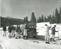 Thumbnail for 'A cross country club or team prepare for action along the road, next to their school bus transportation.  ca. 1957.'