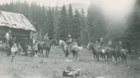 Thumbnail for 'Hiking and Outing Club members, some on horseback, gather outside a rustic cabin, early 1930s.'