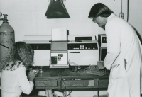 Thumbnail for 'A student and lab assistant work with a piece of Hurst Hall equipment, circa 1990.'