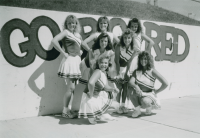 Thumbnail for 'The Western Cheerleading squad pose for a photograph at the entrance to Mountaineer Bowl, late 1980s.'