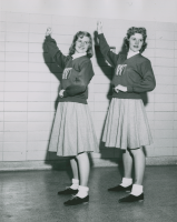 Thumbnail for 'Two Western cheerleaders pose in a Mountaineer Gymnasium hallway, early 1950s.'