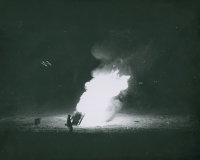 Thumbnail for 'A lone figure attends the traditional Homecoming bonfire, probably in Mountaineer Bowl, 1958.  The lighted 